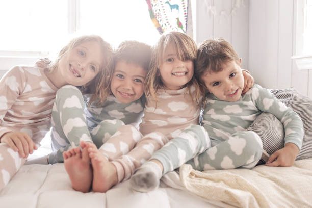 Four young kids in pajamas laughing together for a family group photo